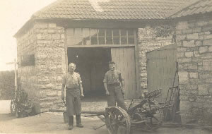 George Clist (61 yrs) and his nephew Ted Rossiter (39 yrs) at the Smithy, c. July 1924. Street sign to Taunton at left.